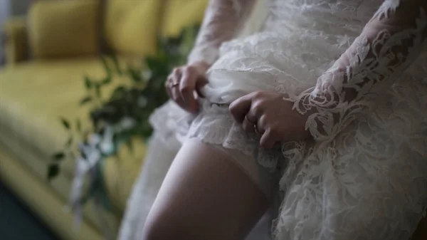 A noiva veste meias em pernas. noiva de beleza em um vestido usando meias casamento dentro de casa. Retrato feminino senhora agradável em um vestido. Fechar as mãos da mulher — Fotografia de Stock