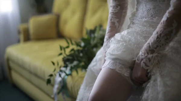 Vestidos de novia medias en los pies. Belleza novia en un vestido con medias de boda en el interior. Mujer retrato agradable dama en un vestido. Primer plano de las manos de la mujer — Foto de Stock