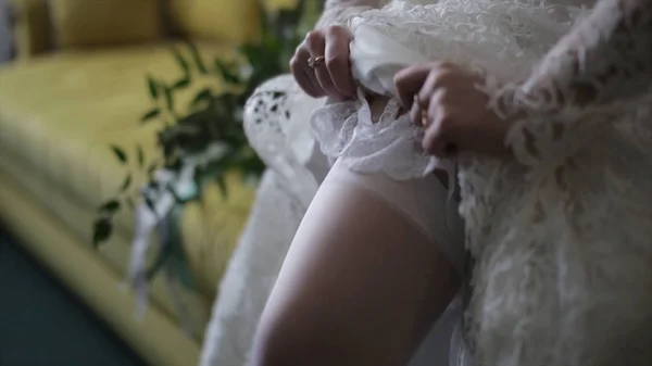 A noiva veste meias em pernas. noiva de beleza em um vestido usando meias casamento dentro de casa. Retrato feminino senhora agradável em um vestido. Fechar as mãos da mulher — Fotografia de Stock