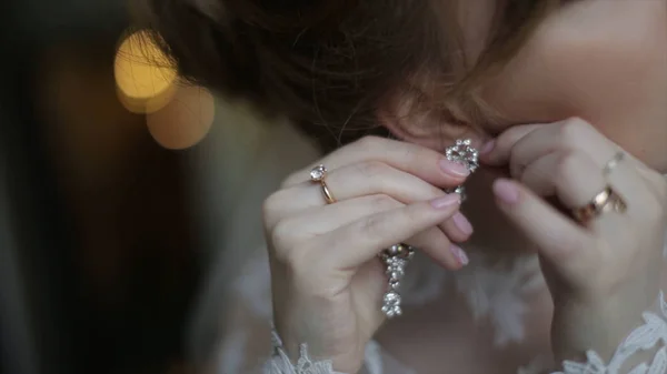 Belle mariée dans met sur boucle d'oreille. Belle fille modèle porte des bijoux pour le mariage. Portrait féminin de mariage. Femme aux cheveux bouclés et voile de dentelle. concept de bijoux et de beauté - gros plan sur le port — Photo