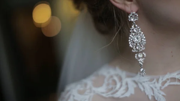 Beautiful bride in puts on earring. Beauty model girl is wearing jewelry for marriage. Wedding female portrait. Woman with curly hair and lace veil. jewelry and beauty concept - close up of wearing — Stock Photo, Image