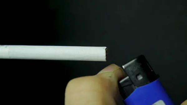 Éclairage à la main briquet cigarette gros plan. Brûler la cigarette sur fond noir. Gros plan de cigarette sur fond noir — Photo