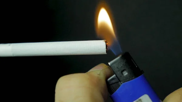 Handfeuerzeug Zigarettenanzündung Nahaufnahme. brennende Zigarette auf schwarzem Hintergrund. Zigarette Nahaufnahme auf schwarzem Hintergrund — Stockfoto