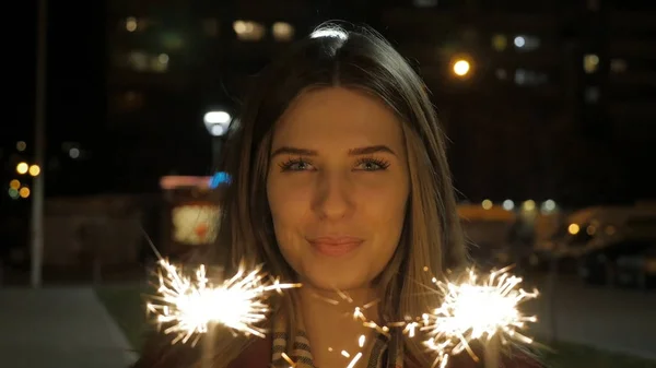 Mooie lachende jonge vrouw met een sparkler. Nachtscène. Lachende meisje sparkler met in haar hand. Concept vakantie — Stockfoto