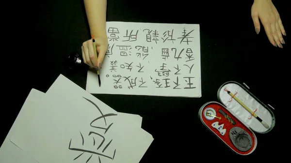 女性の手が米紙に筆と墨を使用して中国の書道を書きます。クローズ アップ手に保持ブラシ書道を書き込み中。中国の絵画・書道 — ストック写真