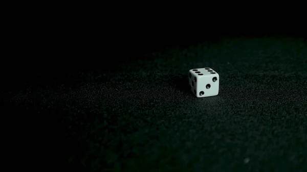 Female hand throwing dice on black background in slow motion. Two standard six-sided pipped dice with rounded corners on black background.