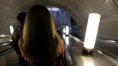 Dikiz kız kız metroda yürüyen merdiven aşağı. Kadın üzerinden yürüyen merdiven tounel metro istasyonu'na iniyor. bir metro istasyonunda bir yürüyen merdiven yukarı sürme kadın