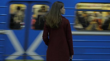 İçin gelen tren bekleyen kız Metro istasyonunda. Dikiz tren istasyonunda bekleyen kız. Tren geldiğinde