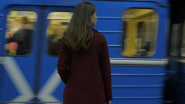 İçin gelen tren bekleyen kız Metro istasyonunda. Dikiz tren istasyonunda bekleyen kız. Tren geldiğinde