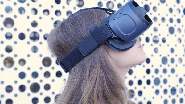 Mulher usando um fone de ouvido de realidade virtual em fundo futurista branco. Jovem mulher atraente usando óculos VR-fone de ouvido — Fotografia de Stock