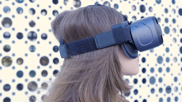 Mulher usando um fone de ouvido de realidade virtual em fundo futurista branco. Jovem mulher atraente usando óculos VR-fone de ouvido — Fotografia de Stock