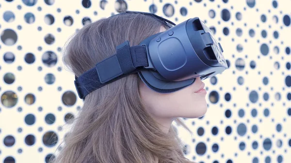 Mulher usando um fone de ouvido de realidade virtual em fundo futurista branco. Jovem mulher atraente usando óculos VR-fone de ouvido — Fotografia de Stock