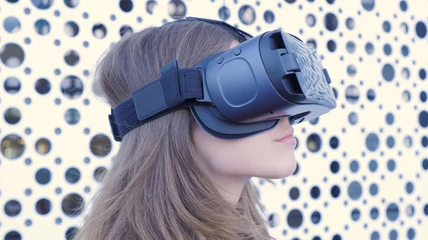 Mulher usando um fone de ouvido de realidade virtual em fundo futurista branco. Jovem mulher atraente usando óculos VR-fone de ouvido — Fotografia de Stock