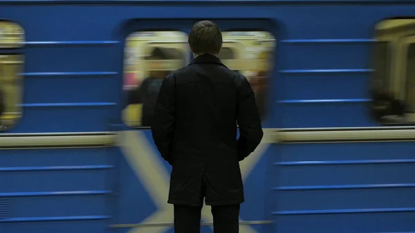 Widok z tyłu samotny młody człowiek zastrzelony na stacji metra dodać patrzeć na zegarek, czekając na pociąg. Biznesmen na stacji — Zdjęcie stockowe