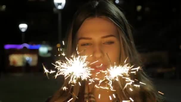 Jeune fille souriante tenant scintillant dans sa main. Portrait de fille tenant des étincelles au ralenti — Video