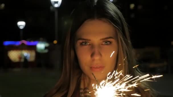 Lachende meisje sparkler met in haar hand. Portret van een meisje houden schittert in slow motion — Stockvideo