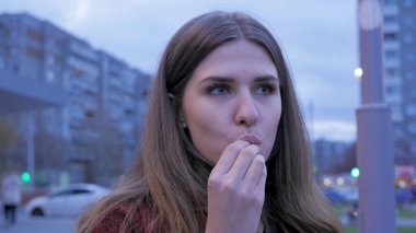 Bir genç kızın kasaba meydanında yemek lokanta var. Kentsel bir sokakta duran ve patates kızartması yiyen genç kadın. Genç kadın sokakta lokanta ayakta yemek