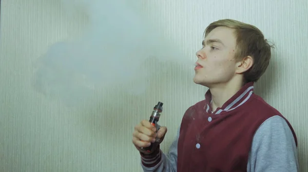 Nuori mies polttaa sähkötupakkaa. Nuori mies käyttäen Vapourizer tupakointi vaihtoehtona — kuvapankkivalokuva