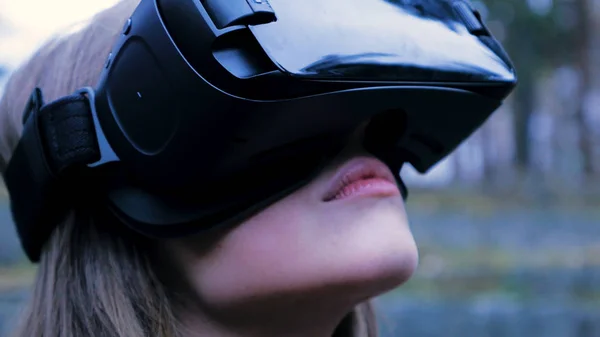 Mulher bonita com realidade virtual no parque ao ar livre. dispositivo óculos de fone de ouvido VR. Uma jovem com óculos de realidade virtual no Parque. Close-up — Fotografia de Stock