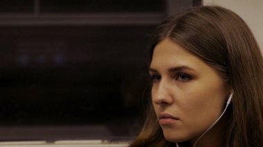 Genç kadın kulaklıklar müzik dinlemek metro trene biniyor. Yolda müzik ile. Genç kadın metroya biniyor ve kulaklıklar müzik dinlemek.