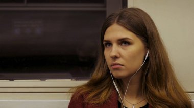 Genç kadın kulaklıklar müzik dinlemek metro trene biniyor. Yolda müzik ile. Genç kadın metroya biniyor ve kulaklıklar müzik dinlemek.
