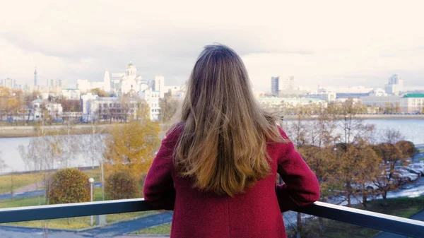 Achteraanzicht van de vrouw permanent op balkon en genieten van het uitzicht op de stad. Achteraanzicht van jonge vrouw staande op het balkon — Stockfoto