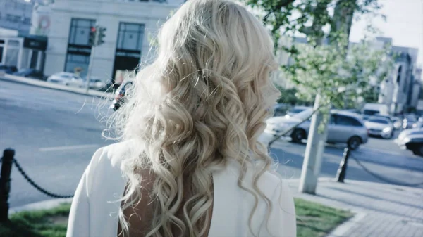 魅力的な金髪のビジネス女性が街を歩いてします。カメラに背中を街を歩いてビジネス女性 — ストック写真