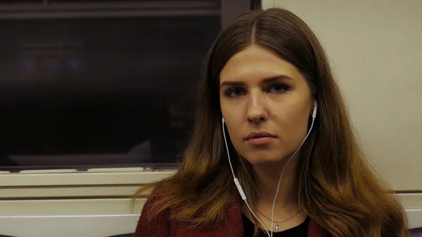 Молодая женщина едет на метро, слушая музыку в наушниках. С музыкой на дороге. Молодая женщина ездит в метро и слушает музыку в наушниках . — стоковое фото