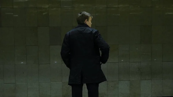 Samotny młody człowiek od tyłu na stacji metra. Młody człowiek czeka na pociąg w metrze, widok z tyłu — Zdjęcie stockowe