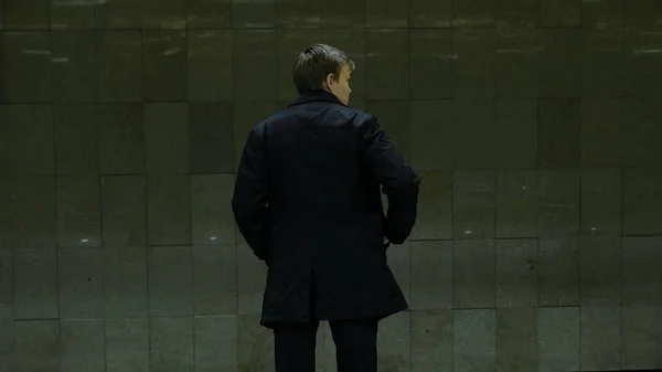 Lonely young man from behind at subway station. Young man waits for a train in the subway, rear view — Stock Photo, Image