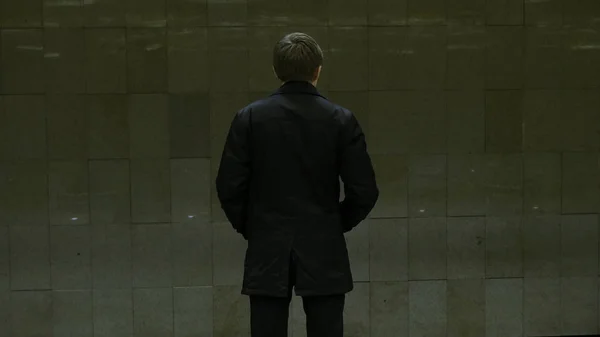 Lonely young man from behind at subway station. Young man waits for a train in the subway, rear view — Stock Photo, Image