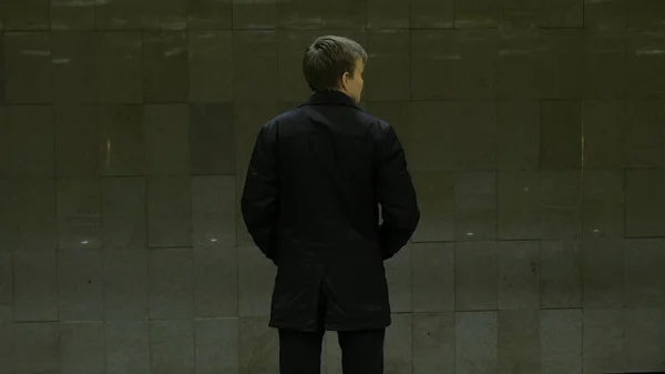 Un joven solitario por detrás en la estación de metro. Joven espera un tren en el metro, vista trasera — Foto de Stock