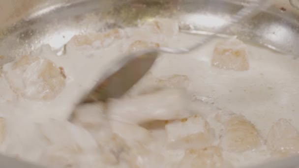 Närbild av kycklingkött med mjölk remsor matlagning på en varm kastrull på en gasspis. Kyckling steka i en stekpanna, ovanifrån. Matlagning stekt kycklingbröst i oljad panorerar på stovetop — Stockvideo