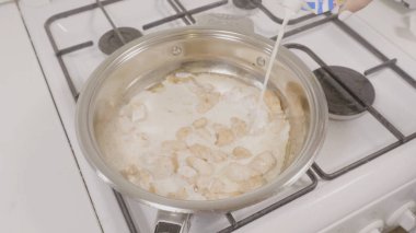 Üstten Görünüm ile tavuk tava süt ekleme. Bir gaz sıcak bir tava pişirme tavuk eti closeup soba. Bir tavada kızartma tavuk