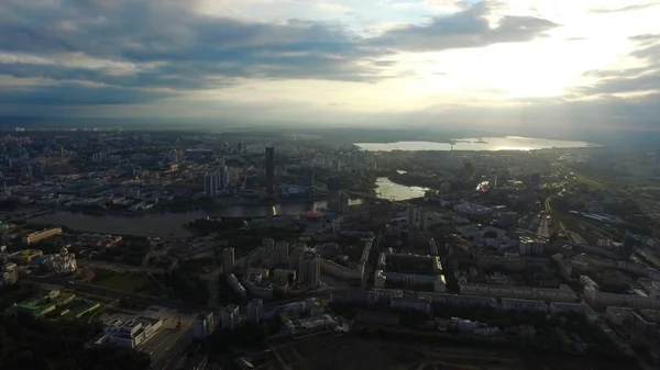 Schöne und atemberaubende Aussicht über die Stadt. Man sieht die Straßen, die Häuser, den großen Wolkenkratzer, die Sonnenstrahlen brechen durch die Wolken — Stockfoto