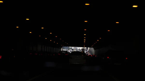 Asphalt road under the steel construction of a bridge in the city. Night urban scene with car light trails in the tunnel — Stock Photo, Image