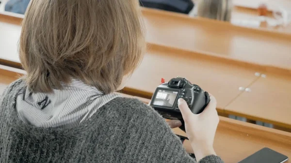 Jovem fotógrafo feliz assistindo fotos na câmera. Jovem mulher assistindo fotos na câmera na sala — Fotografia de Stock