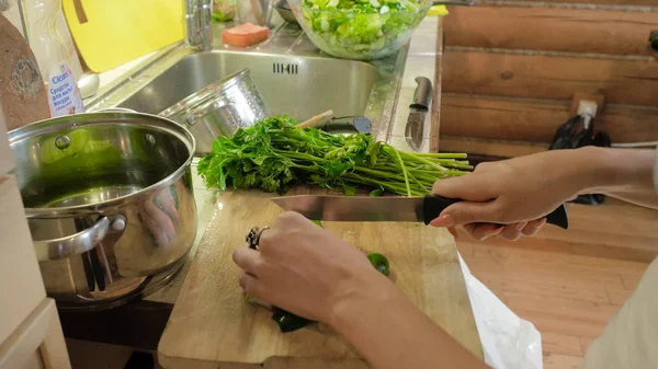 Kadın mutfakta salata hazırlanıyor. Çekici kız kesim salatalık salatası mutfağında evde yaparken. Genç kadın mutfakta bir salatalık keser