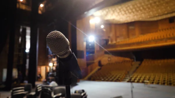 Mikrofon di atas panggung dan aula kosong selama latihan. Mikrofon di atas panggung dengan lampu panggung di latar belakang. Mikrofon di atas panggung di aula kosong — Stok Foto