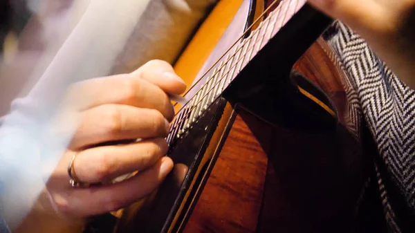 Closeup bela guitarra acústica sendo tocada por mulher sentada, conceito músico. Mulher tocando a guitarra close-up — Fotografia de Stock