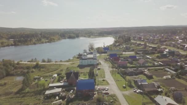 Aerial view of the European village near the pond. Beautiful aerial view of Color Lake and village with church. Top view of the village and pond — Stock Video