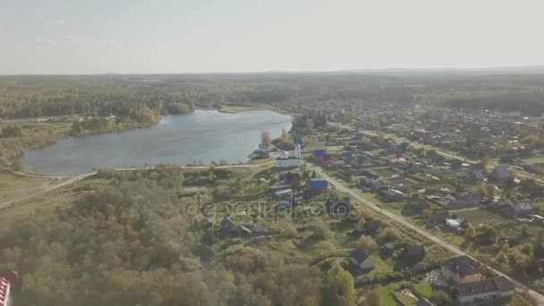 Luchtfoto van het Europees dorp in de buurt van de vijver. Mooie luchtfoto van kleur meer en dorp met kerk. Bovenaanzicht van het dorp en de vijver — Stockvideo