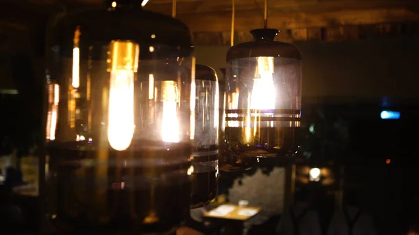 Ζεστό φωτισμό βγαίνοντας από όμορφη λαμπτήρες ενώ παίρνετε ένα ζεστό φλιτζάνι καφέ σε μια μοντέρνα καφετέρια με ωραίο περιβάλλον — Φωτογραφία Αρχείου