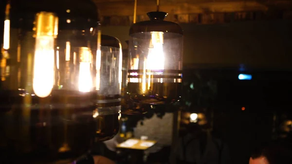 Příjemné osvětlení pochází krásné lampy přičemž horký šálek kávy v módní kavárně s pěkné prostředí — Stock fotografie