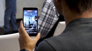 Başka bir adam sahnede gerçekleştirdiğinde erkek el bir telefon ile büyük bir olay video vuruyor. Adam ateş nasıl bir iş planı sunan adam sahnede, performans video