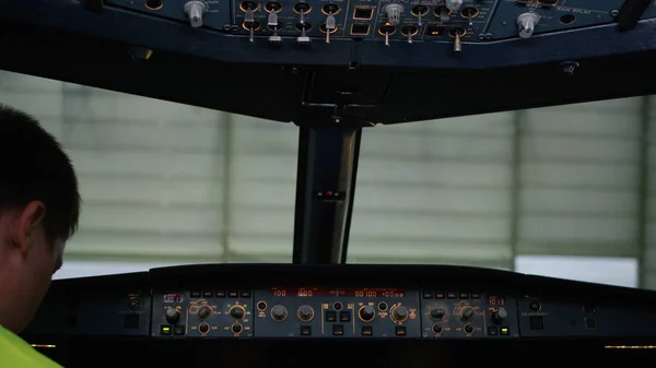 Um piloto a verificar instrumentos num cockpit de avião. Visão traseira dos controles de operação do piloto do jato corporativo. O piloto verifica todos os sistemas. Vista traseira dos controlos de funcionamento do piloto e do co-piloto de — Fotografia de Stock