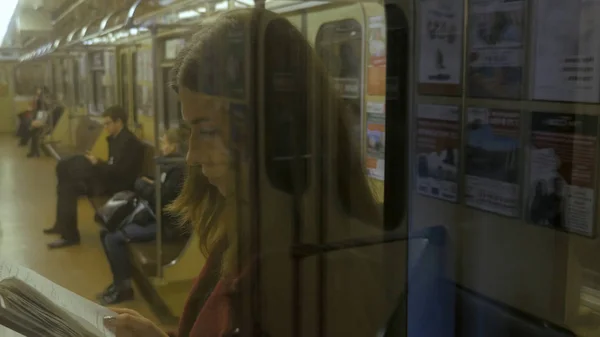 Hermosa chica leyendo un libro en tren en el metro. Adolescente chica leer un libro en tren — Foto de Stock