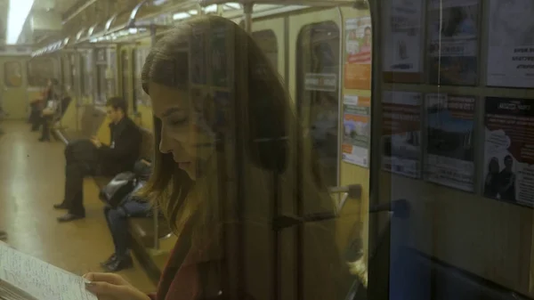 Piękna dziewczyna z książką w pociągu na stacji metra. Dziewczyna nastolatek, poczytać książkę w pociągu — Zdjęcie stockowe