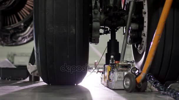 Aircraft brake repair. Close up of airplane wheel and shaft. Huge airplane tyre with shaft and landing gear of plane under airplane. Engineer fixing aircrafts wheel — Stock Video