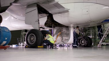 Muayene ve uçak önce hazırlama çıkar. Yolcu uçakları şasi, hangar uçuş öncesi bakım. Havaalanı işçilerin mekanik